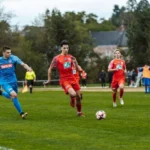 Dynamic football match action captured in France with players in red and blue jerseys.