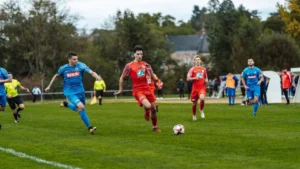 Dynamic football match action captured in France with players in red and blue jerseys.