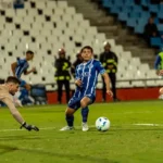 Dynamic shot of soccer players in action during a competitive match on a well-lit field.